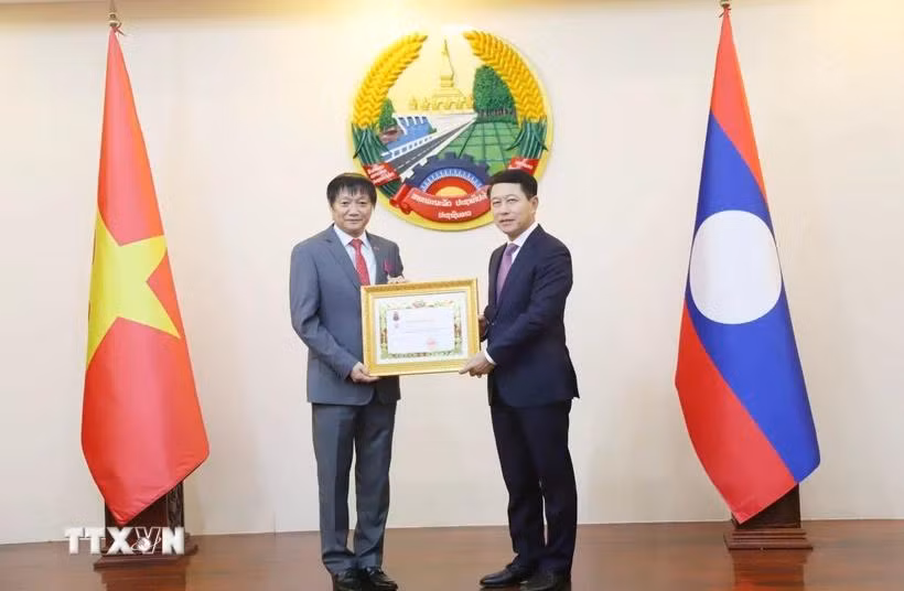 Phó Thủ tướng Lào Saleumxay Kommasith (phải) trao tặng Huân chương Tự do hạng Ba cho Đại sứ Việt Nam tại Lào Nguyễn Bá Hùng. (Ảnh: Xuân Tú/TTXVN)