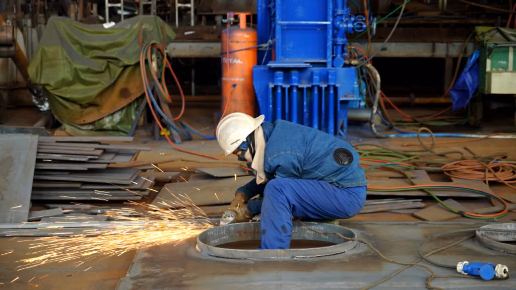 Những người công nhân trong bộ đồ bảo hộ kín mít, miệt mài làm việc.