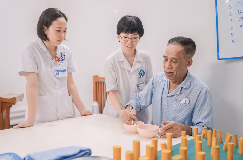 Chuyên gia Kamikawa Mariko (đứng giữa) cùng bệnh nhân Nguyễn Văn Tâm (phường Vàng Danh, TP Uông Bí) thực hiện các bài tập vận động cơ bản.