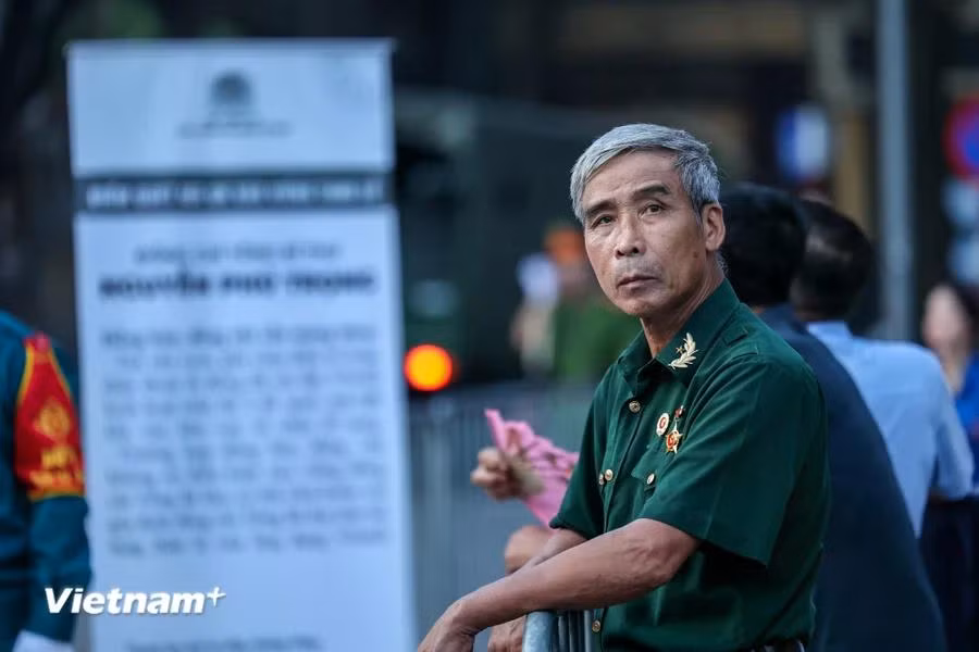 Trong dòng người xếp hàng trên đường Trần Hưng Đạo có ông Nguyễn Văn Quế đến từ Mê Linh, Hà Nội. Ông Quế cho biết mình có mặt tại đây từ 3 giờ sáng nhưng đã có nhiều người dân đứng xếp hàng từ trước. "Là một người dân, người cựu chiến binh tôi rất cảm phục trước tấm lòng của Tổng Bí thư vì nhân dân vì đất nước. Tôi đến đây với niềm mong mỏi được gặp Tổng Bí thư lần cuối." (Ảnh: Minh Sơn/Vietnam+)
