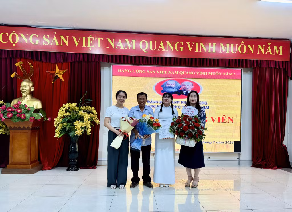 Đại diện Đảng ủy trường tặng hoa chúc mừng các đồng chí đảng viên mới. Ảnh do đơn vị cung cấp