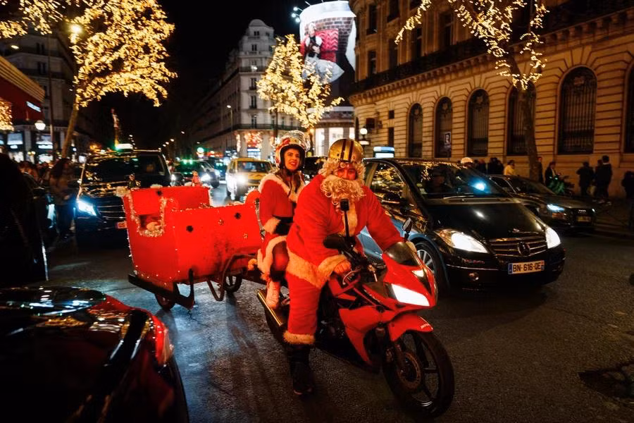Một cặp đôi trong trang phục Ông già Noel chào đón Giáng sinh tại Paris (Pháp), ngày 23/12/2023. (Ảnh: AFP/TTXVN)