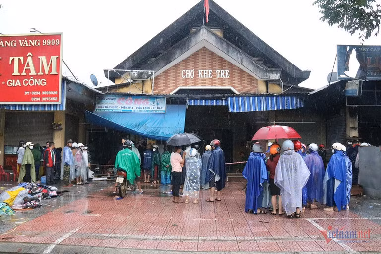 Hàng chục tiểu thương bất chấp mưa nặng hạt, lặng người nhìn vào tài sản của mình bên trong khuôn viên chợ
