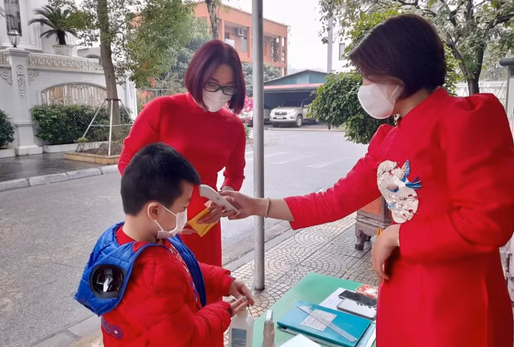 Tại nhiều trường học, các cô giáo đón trẻ ngay từ cổng trường, đo thân nhiệt và hướng dẫn các em học sinh rửa tay sát khuẩn.