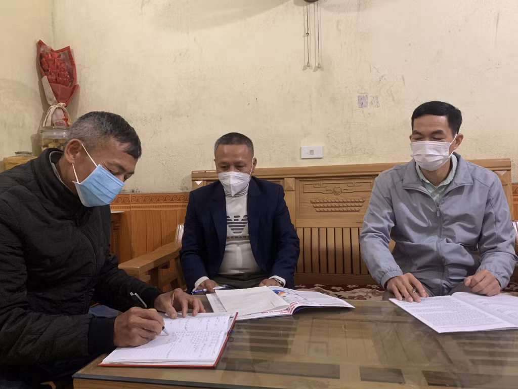 Ông Nguyễn Đức Chính (bên trái) cùng cán bộ thôn, xã bàn biện pháp quản lý người dân về quê đón Tết Nguyên đán 2022.