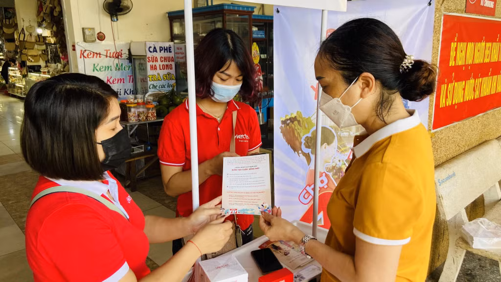 Nhân viên Viettel Quảng Ninh hướng dẫn khách hàng ại Chợ Hạ Long I, TP Hạ Long cài đặt ứng dụng Viettel Money để thanh toán không dùng tiền mặt. Ảnh Hoàng Nga