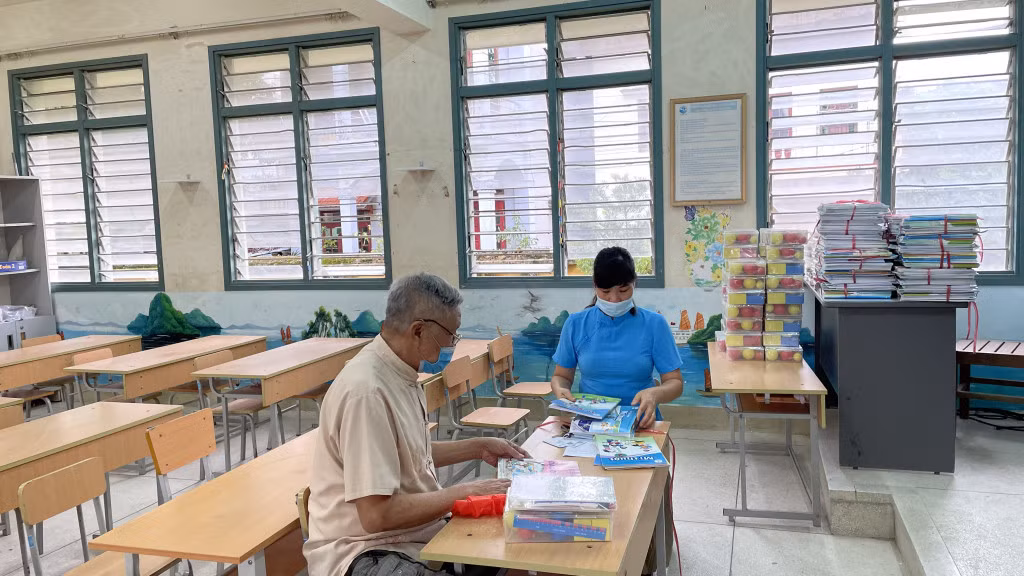 Giáo viên Trường Tiểu học thị trấn Bình Liêu (huyện Bình Liêu) phát SGK lớp 2 mới cho đại diện gia đình học sinh trước khi chính thức bước vào năm học mới 2021-2022. Ảnh: Lan Anh.