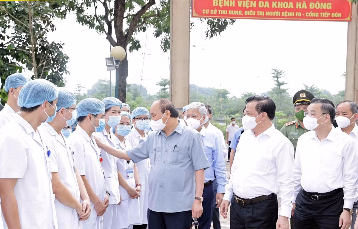 Chủ tịch nước Nguyễn Xuân Phúc thăm hỏi các nhân viên y tế làm việc cơ sở thu dung, điều trị bệnh nhân COVD-19 của Bệnh viện Đa khoa Hà Đông tại phường Hoàng Liệt, quận Hoàng Mai. (Ảnh: Thống Nhất/TTXVN)