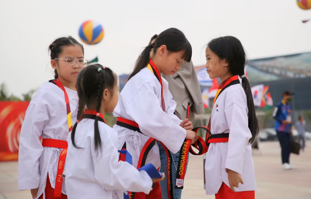 Các bạn nhỏ giúp nhau chỉnh trang phục đúng quy cách trước khi vào thi đấu.