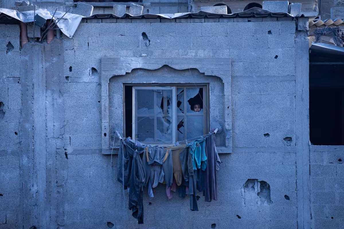 Em bé Palestine nhìn qua cửa sổ vỡ ở Rafah, Dải Gaza, ngày 21/2.