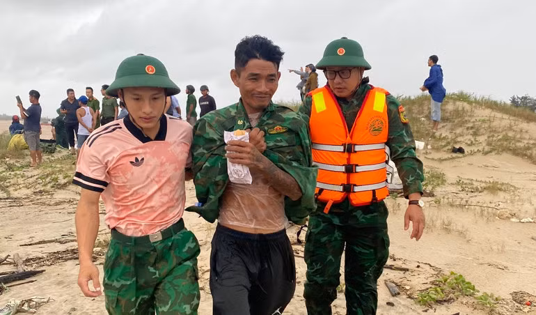 Một ngư dân (giữa ảnh) rời tàu bơi vào bờ, được lực lượng biên phòng hỗ trợ.