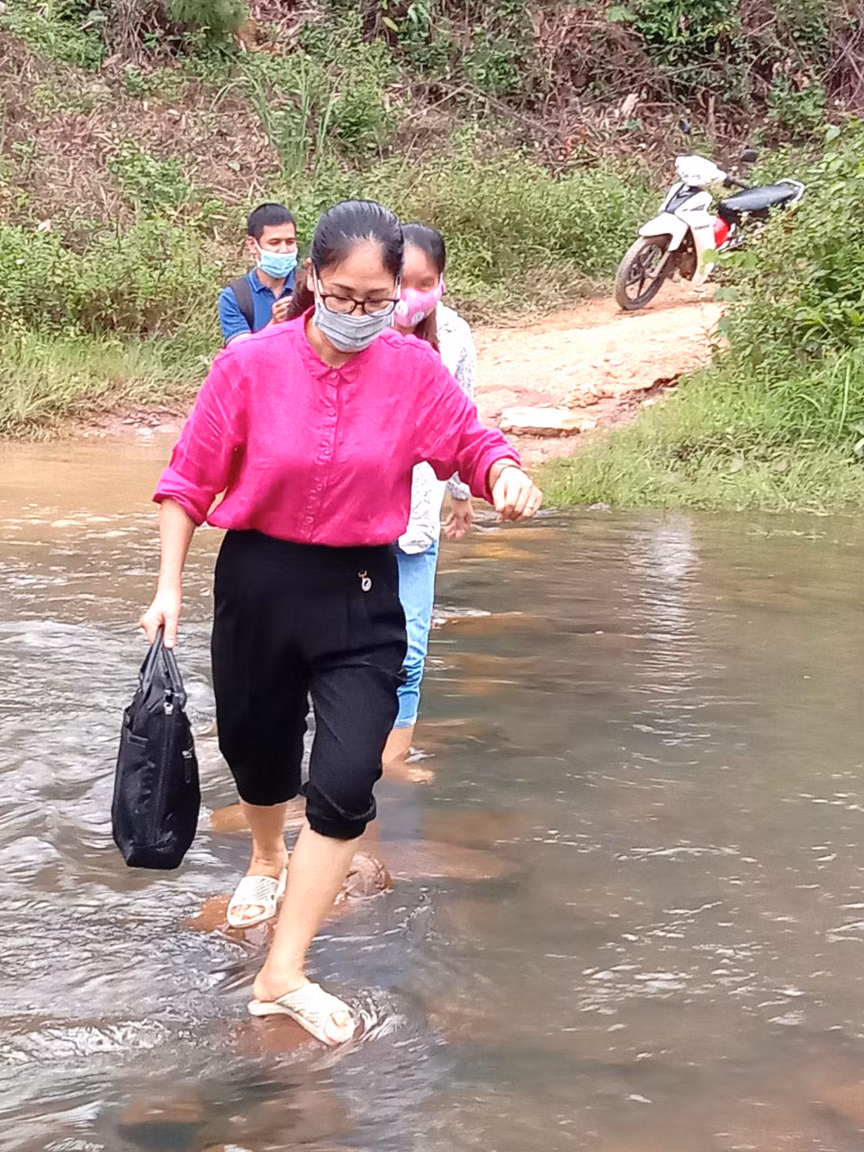Các thầy cô dò dẫm từng bước chân qua suối thôn Pắc Cương, xã Hoành Mô trong một buổi đi vận động học sinh trở lại trường
