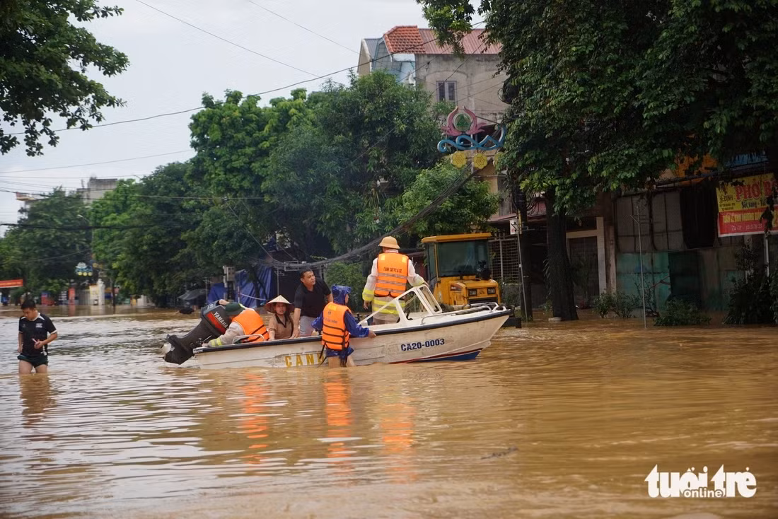Lực lượng chức năng hỗ trợ người dân chạy lũ - Ảnh: VŨ TUẤN
