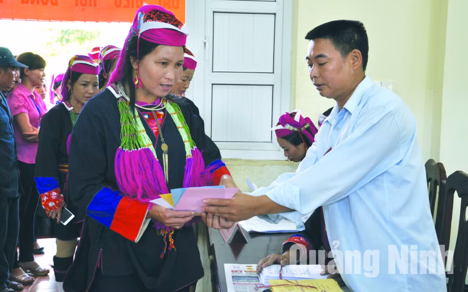 Anh Nịnh Văn Bằng, thành viên tổ bầu cử số 1, thôn Khe Tâm, xã Nam Sơn (Ba Chẽ) hướng dẫn cử tri đồng bào dân tộc Dao Thanh Y làm thủ tục bỏ phiếu. Ảnh: Hồng Nhung