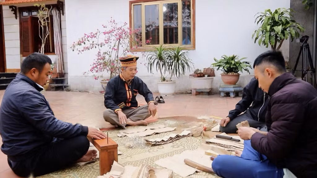 Ông Triệu Đức Liên (người có uy tín thôn Hang Trăn, xã Quảng La) hướng dẫn cách làm vàng mã thủ công bằng giấy bản trong ngày Tết nhà trưởng.