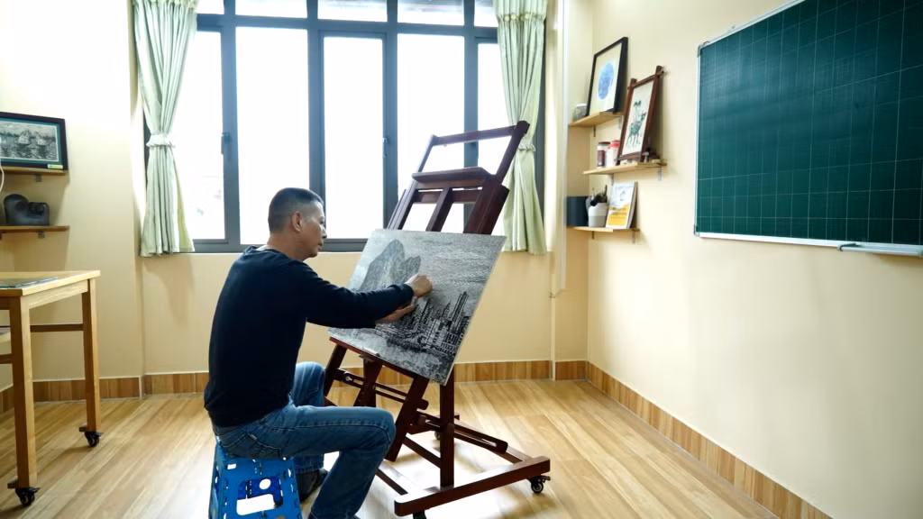 Họa sĩ Hải Thanh đang thực hiện tạo hình bố cục tranh trên bản khắc gỗ.