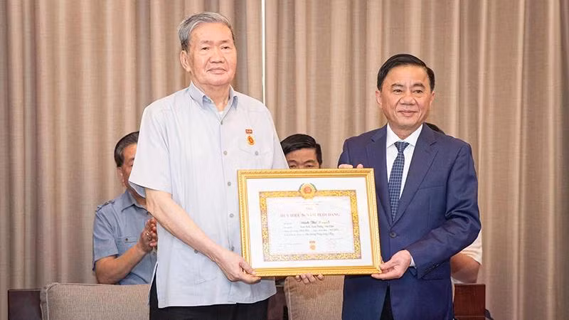 Đồng chí Trần Cẩm Tú trao Quyết định tặng Huy hiệu 50 tuổi Đảng cho đồng chí Đinh Thế Huynh. (Ảnh: Sơn Tùng)