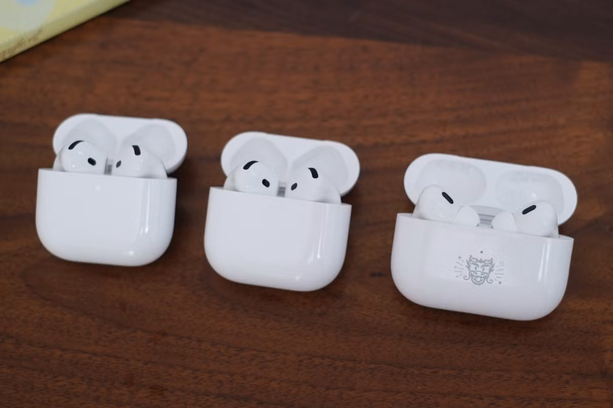 Hai phiên bản AirPods 4 so dáng với AirPods Pro 2 (bên phải). Hộp sạc bản Pro có chiều ngang lớn hơn trong khi tai nghe có thêm phần đệm cao su đặc trưng. Tất cả đều cho phép tùy chọn hình khắc miễn phí nếu mua qua trang bán hàng trực tuyến của Apple.