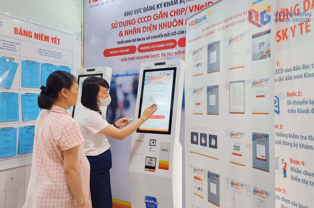 Nhân viên công tác xã hội Bệnh viện Bãi Cháy hướng dẫn người dân đăng ký khám bệnh trên hệ thống ki-ốt thông minh.