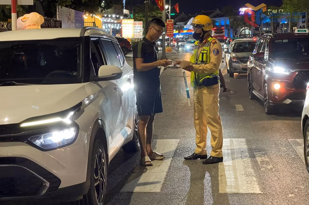 Cán bộ Đội CSGT đường bộ số 2, Phòng CSGT (Công an tỉnh) nhắc nhở du khách ngoại tỉnh dừng, đỗ xe đúng nơi quy định tại khu du lịch Bãi Cháy. Ảnh: Hồng Việt