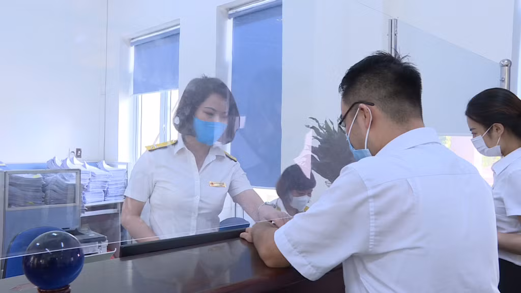 Cán bộ Chi cục Thuế TX Đông Triều hướng dẫn người dân điền tờ khai lệ phí.