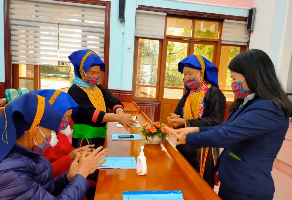 Cán bộ Ban Dân tộc tỉnh hướng dẫn bà con DTTS huyện Ba Chẽ khử khuẩn trước khi vào hội nghị tuyên truyền pháp luật năm 2020. Ảnh: Nguyên Ngọc
