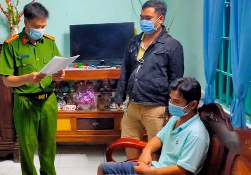 Trí (ngồi) tại thời điểm bị bắt giữ.