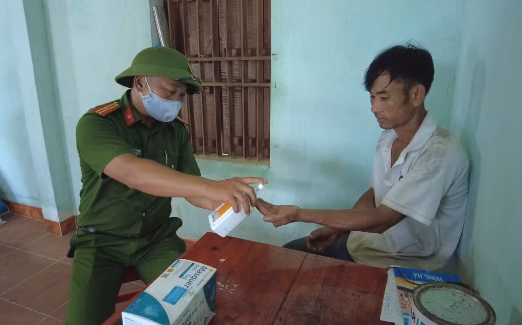 Trưởng công an xã Quảng Sơn - Phùn Phúc Khường hướng dẫn người dân sát khuẩn đảm bảo phòng dịch.