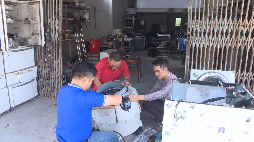 Anh Vũ Duy Thế (áo đỏ) cùng thợ sửa đồ cho khách.