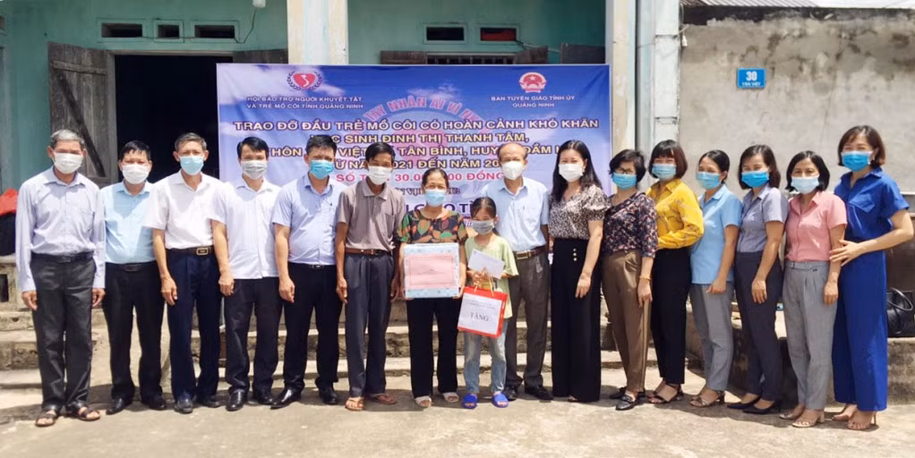 Lãnh đạo Ban Tuyên giáo Tỉnh ủy, Hội Bảo trợ NKT&TMC tỉnh, huyện Đầm Hà trao đỡ đầu trẻ mồ côi cho em Đinh Thị Thanh Tâm, học sinh Trường Tiểu học xã Tân Bình.