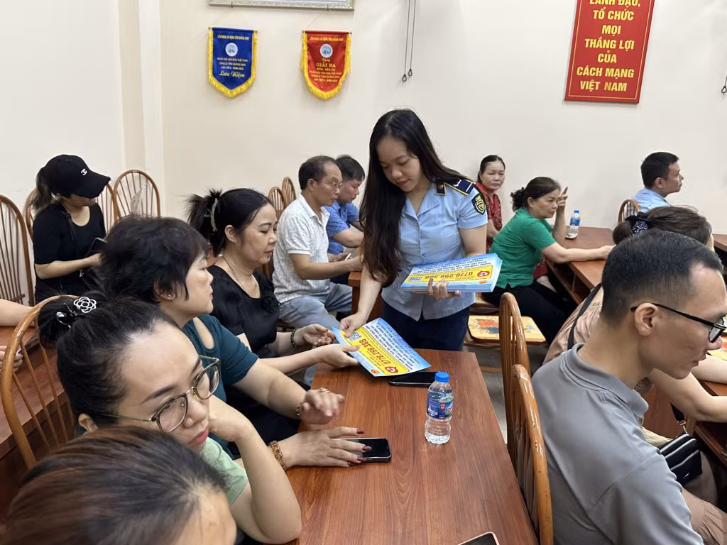 Đại diện Đội QLTT số 5 phát tờ rơi tuyên truyền pháp luật cho các tiểu thương, hộ kinh doanh tham dự.