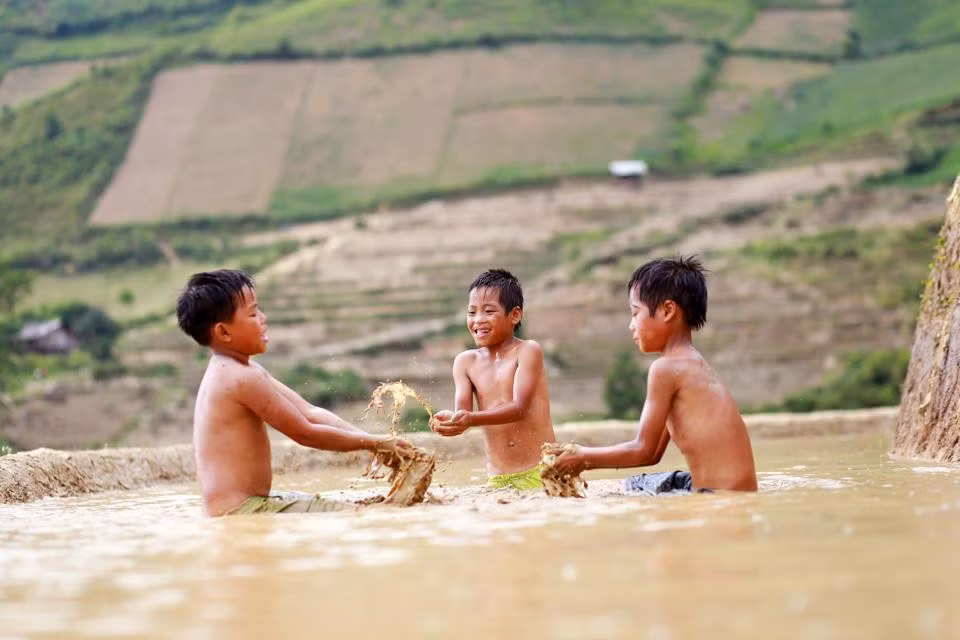 Những đứa trẻ người Mông tranh thủ chơi đùa bên những thửa ruộng bậc thang đã được đổ nước.