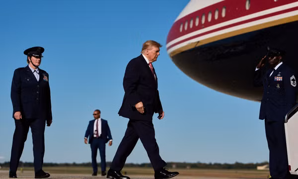 Tổng thống Mỹ Donald Trump đi từ trực thăng Marine One tới chuyên cơ Không lực Một tại Căn cứ liên hợp Andrews, bang Maryland, ngày 19/10/2026, cùng Đại tá Melissa Dombrock (trái), Phó Tư lệnh Không đoàn Vận tải số 89. Ảnh: AP