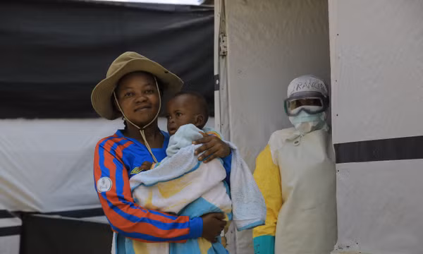 Bé Kavugho Mayolo Latifa, 1 tuổi (có mẹ qua đời vì Ebola), được chị gái Leandrine Kavira bế sau khi đã hồi phục khỏi căn bệnh này tại buổi lễ xuất viện ở một trung tâm điều trị tại thành phố Beni, thuộc tỉnh Bắc Kivu, miền đông Congo, ngày 26/9/2026. Ảnh: AP