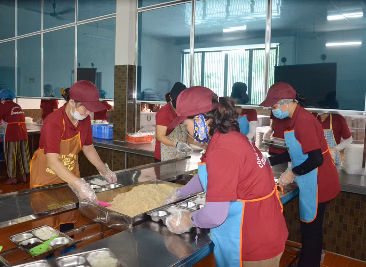 Nhân viên Công ty CP Hồng Đức chia cơm cho học sinh cho 4 trường tiểu học trên địa bàn TP Hạ Long.