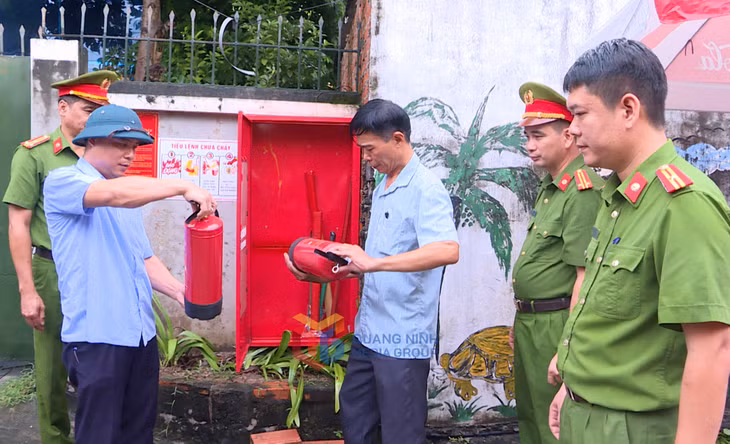 Công an TP Hạ Long hướng dẫn người dân cách sử dụng bình chữa cháy được trang bị tại "Điểm chữa cháy công cộng" phường Hồng Gai. Ảnh: Lê Nam