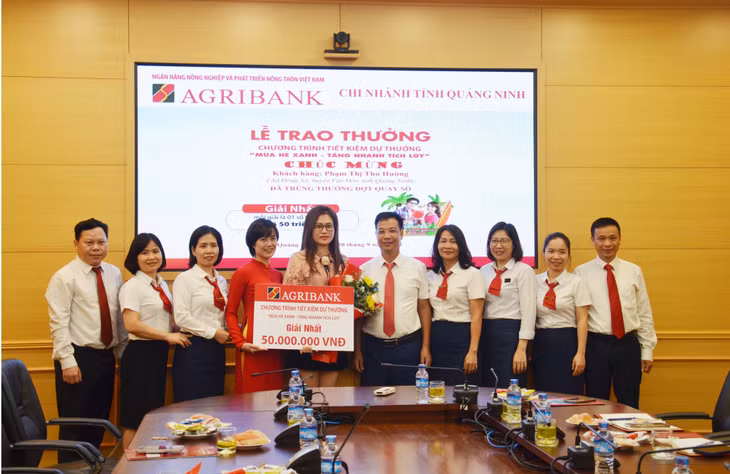 Cán bộ, nhân viên Agribank Quảng Ninh chụp ảnh cùng khách hàng trúng thưởng giải Nhất.