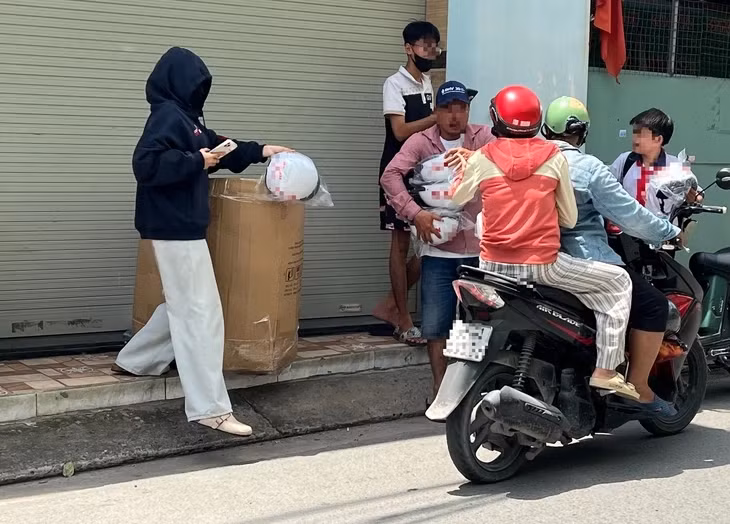 Từ học sinh, người dân, bất kể ai ghé lại đều được tặng nón bảo hiểm có chứa hình ảnh quảng cáo cờ bạc online trá hình một cách miễn phí - Ảnh: TRIỆU VÂN