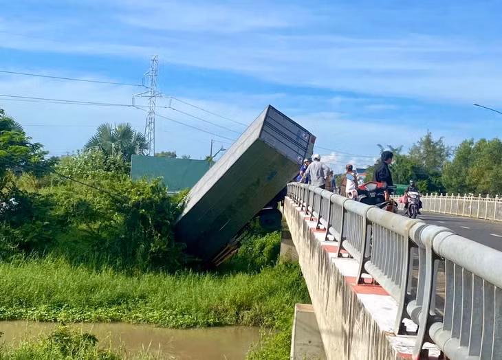 Hiện trường xe tải cắm đầu xuống sông, phần đuôi kẹt lại trên thành cầu. Ảnh: Duy Tuấn