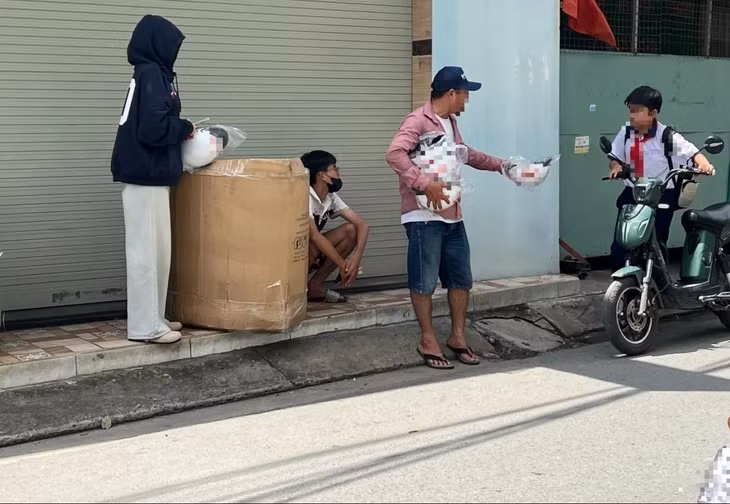 Một học sinh khi dắt xe đi ngang qua cũng được phát nón miễn phí. Ảnh chụp trên đường Cống hộp, phường Bình Tân vào lúc 12h15 ngày 4-10 - Ảnh: TRIỆU VÂN