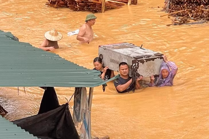Người dân ở Lạng Sơn đưa tài sản qua vùng nước lũ đặc quánh màu bùn đất - Ảnh: MXH