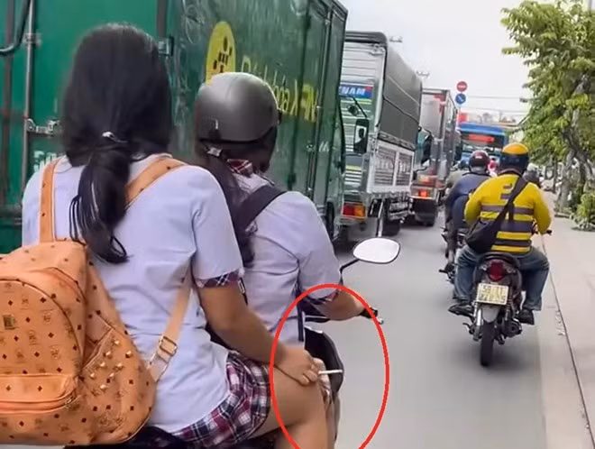 CSGT đang xác minh nữ sinh đi xe máy không đội mũ bảo hiểm, tay cầm thuốc lá ở TPHCM. Ảnh: Đông Hoàng