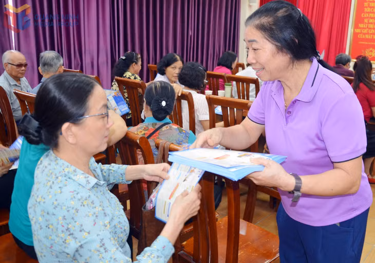 Đại diện của Tổ chức dịch vụ thu BHXH, BHYT phát tờ rời tuyên truyền chính sách BHXH tự nguyện cho các đại biểu tại hội nghị.