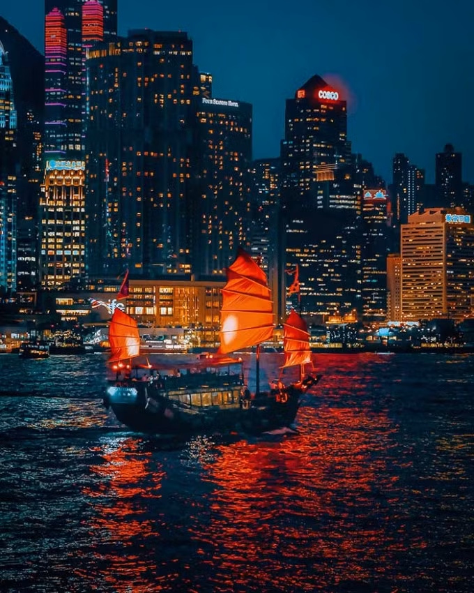 Cánh buồm đỏ nổi bật, biểu tượng của Hong Kong, lênh đênh trên vịnh Victoria. Hình ảnh cánh buồm rẽ sóng, qua lại hai bên bờ - bán đảo Cửu Long và đảo Hong Kong - được ví như cánh cửa thời gian, nối quá khứ và hiện tại.