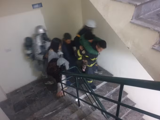 Lực lượng cứu hoả cõng một cụ già thoát khỏi đám cháy. Ảnh: Xuân Hoa