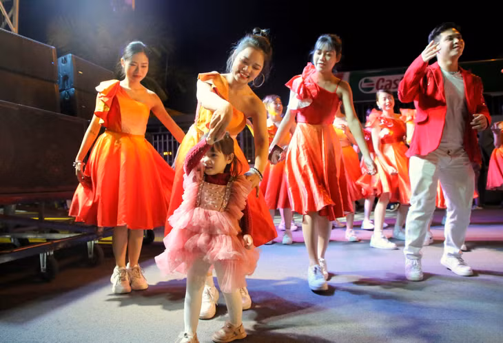 Một khán giả nhí vui tươi nhảy cùng các vũ công đường phố trong đêm hội Carnaval.