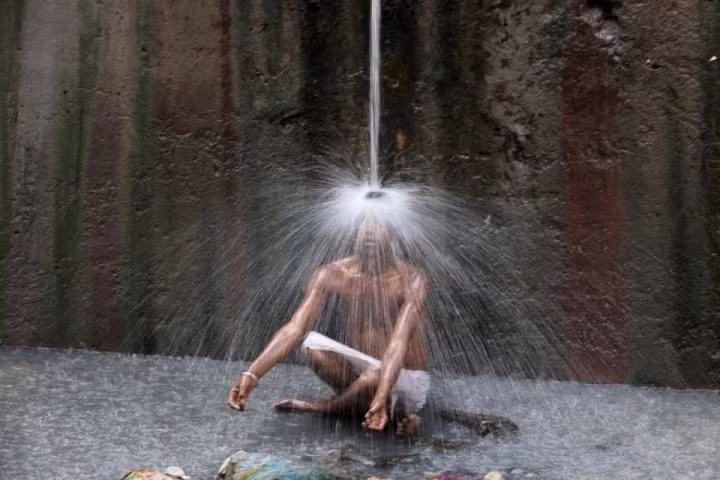 Một người đàn ông "giải nhiệt" dưới vòi nước chảy vào một ngày hè nóng nực ở New Delhi, Ấn Độ, ngày 11/5.