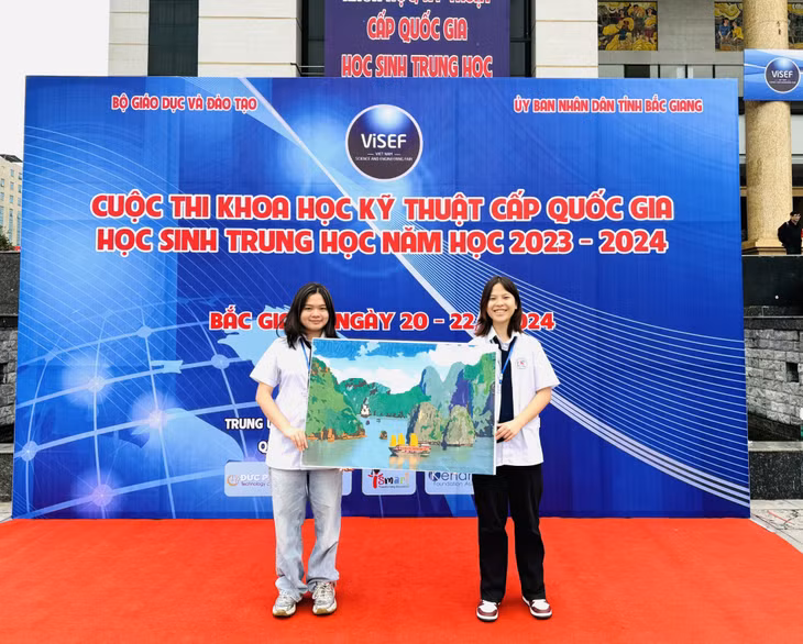 Hai thí sinh mang tranh vẽ cảnh Vịnh Hạ Long giới thiệu tại Lễ khai mạc Cuộc thi. Ảnh: Sở GD&amp;ĐT cung cấp