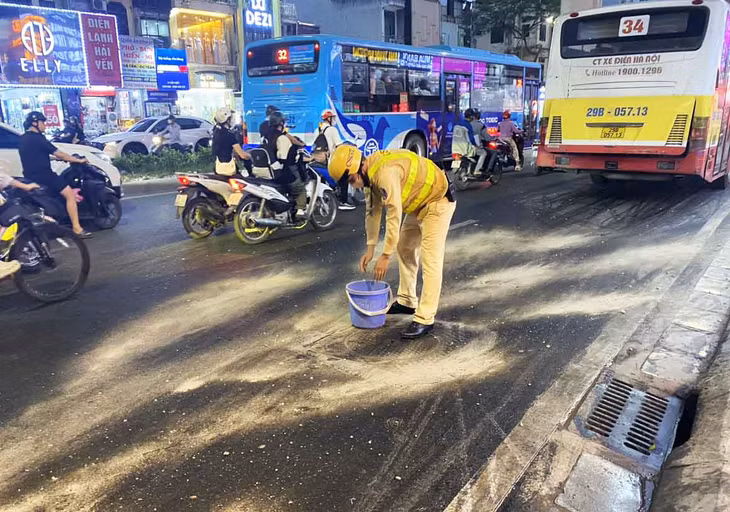 Lực lượng CSGT dùng cát và chổi để dọn vết dầu trên đường. Ảnh: Đình Thành