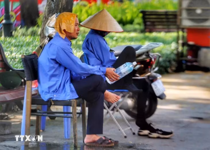 Cái khăn mặt ướt cùng chai nước là vật không thể thiếu của những nhân viên trông xe vỉa hè. (Ảnh: Tuấn Đức/TTXVN)